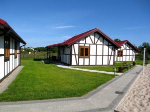 a small house with a grassy yard next to a building at 4 Domki in Sarbinowo