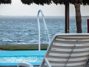 a chair sitting next to a swimming pool with the ocean at Pousada Jagatá in Tutóia