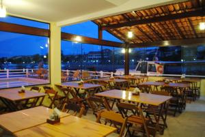 un restaurante con mesas y sillas de madera y un barco en Pousada Porto Canal, en Cabo Frío