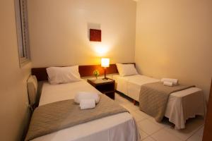 a hotel room with two beds and a lamp at Pampulha Flat in Belo Horizonte