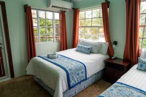 a bedroom with two beds and windows at Island Magic Beach Resort in Caye Caulker