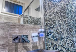 a bathroom with a shower with a sink and a mirror at Tribunale Basement Apartment in Messina