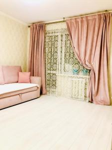 um quarto com uma cama e uma janela com cortinas cor-de-rosa em Classic Apartment em Boryspil
