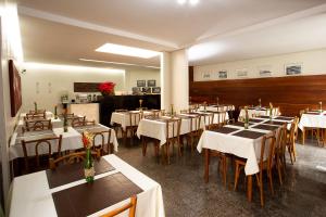 um restaurante com mesas e cadeiras com toalha de mesa branca em Pampulha Flat em Belo Horizonte