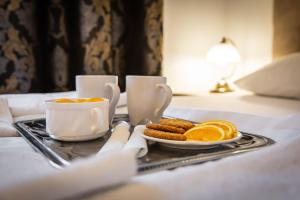 a tray with a plate of oranges and a cup of coffee at Gold Rooms in Koszalin