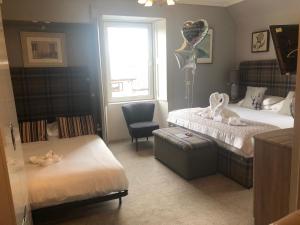 a bedroom with two beds and a chair and a window at Redcliffe Hotel in Inverness