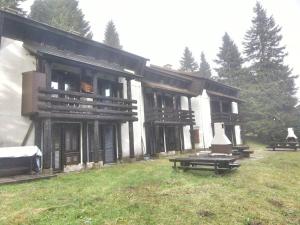 a large wooden building with benches in the grass at Rogla Apartma Gaber54 in Zreče