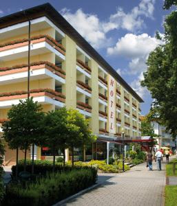 a large building with people walking in front of it at Kurhotel Panland in Bad Füssing