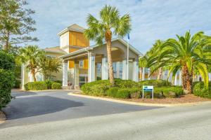 a large house with palm trees in front of it at Holiday Inn Express Saint Simons Island, an IHG Hotel in Saint Simons Island