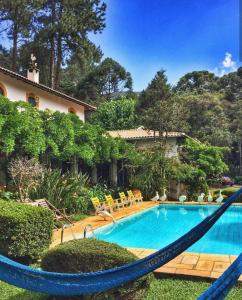 einen Pool mit Hängematte neben einem Haus in der Unterkunft Pousada Villa D'Amore in Monte Verde
