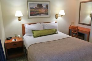 a hotel room with a bed with a green pillow at Candlewood Suites Syracuse-Airport by IHG in North Syracuse +33 photos