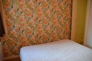 1 dormitorio con pared y papel pintado con motivos florales en Pied de pistes, résidence 3 étoiles tout confort dont terrasse et piscine, en Valmeinier