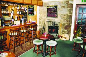 un bar con sillas, mesa y chimenea en The Old Inn, en Gairloch