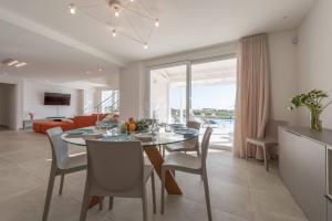 a dining room and living room with a table and chairs at Villa White - IsulaTravel in Modica