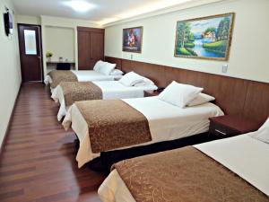 eine Reihe von 4 Betten in einem Hotelzimmer in der Unterkunft Hotel Newen in Temuco