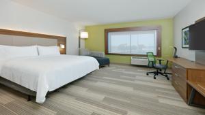 Holiday Inn Express Hotel & Suites Oklahoma City-West Yukon, an IHG Hotel في يوكون: غرفة فندقية فيها سرير ومكتب وتلفزيون