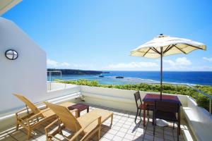 a balcony with a table and chairs and an umbrella at ANA InterContinental Manza Beach Resort by IHG in Onna