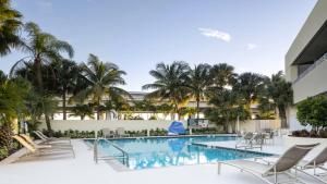 uma piscina no resort com cadeiras e palmeiras em Holiday Inn Palm Beach-Airport Conf Ctr, an IHG Hotel em West Palm Beach