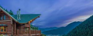 a log cabin with a deck and mountains in the background at Mythica Chalet in Karpenisi