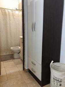 a bathroom with a toilet and a white cabinet at Alojamiento Alelí in Posadas