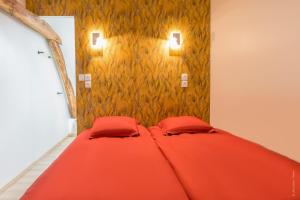 ein rotes Bett in einem Zimmer mit zwei roten Kissen in der Unterkunft Le chant des Mésanges in Boves