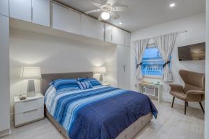 een slaapkamer met een bed met een blauw dekbed en een raam bij Ocean Drive Apartments in Miami Beach
