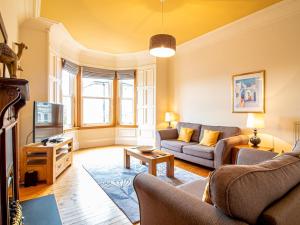 een woonkamer met een bank en een tv bij Pass the Keys Beautiful and Bright Georgian Style Morningside Apartment in Edinburgh