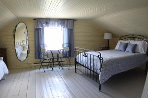 a bedroom with a bed and a window and a mirror at La Grange aux Hiboux Gîte et Restaurant B&B in La Baie