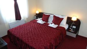 a hotel room with a bed with red sheets and pillows at Villa Bastion in Bitola
