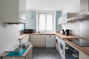 a kitchen with white cabinets and a washer and dryer at Le Hauban by Cocoonr in Saint Malo