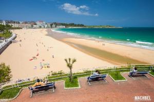 a group of people sitting on benches near a beach at Apartamento Urieli in Santander +4 photos