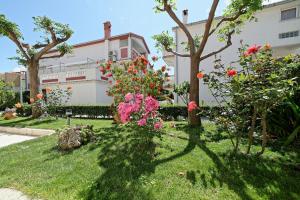 a garden with flowers and trees in front of a building at Apartments Mar - 150 m from sea in Rab