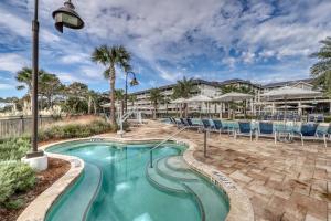 a swimming pool at a resort with chairs and umbrellas at Pink Pineapple in Hilton Head Island