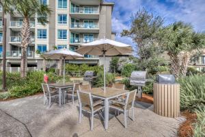 eine Terrasse mit Tischen und Sonnenschirmen vor einem Gebäude in der Unterkunft Pink Pineapple in Hilton Head Island