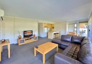 a living room with a leather couch and a table at Del Mar 1 in Mandurah