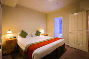 a bedroom with a large white bed with green pillows at Flinders Landing Apartments in Melbourne