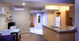 a kitchen with a counter and a table and a refrigerator at Flinders Landing Apartments in Melbourne