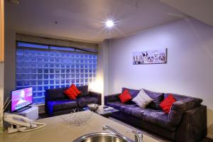 a living room with two couches and a tv at Flinders Landing Apartments in Melbourne