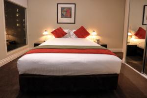 a bedroom with a large bed with red pillows at Flinders Landing Apartments in Melbourne
