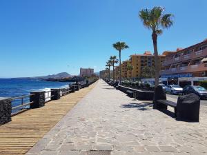 a boardwalk next to the ocean with palm trees and buildings at alquilaencanarias Candelaria, Terrace and Pool ! in Candelaria