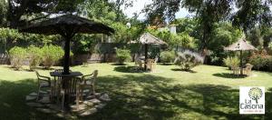 una mesa y sillas en un patio con sombrilla en La Casona de Valeria en Valeria del Mar