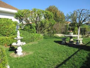 a garden with a table and a fountain in the grass at Les Roses de Rita in Boisset-lès-Montrond