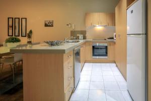 a kitchen with a sink and a white refrigerator at Flinders Landing Apartments in Melbourne