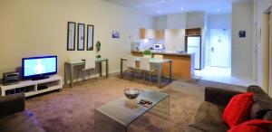 a living room with a couch and a tv and a kitchen at Flinders Landing Apartments in Melbourne