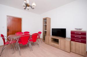 a dining room with red chairs and a table and a television at Apartments Joka in Lopar