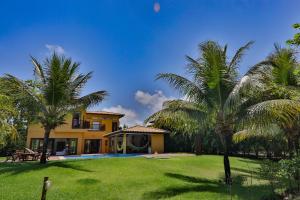 a house with palm trees in front of a yard at Linda casa Costa do Sauipe, piscina, praia particular, muita natureza, Quintas F12 in Costa do Sauipe