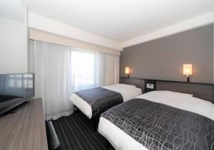 Habitación de hotel con 2 camas y TV de pantalla plana. en APA Hotel Sakai Ekimae en Sakai
