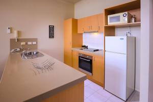 a kitchen with a white refrigerator and a sink at Flinders Landing Apartments in Melbourne