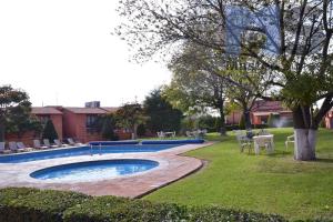 a swimming pool in a yard with tables and chairs at Moderna Suite Alberca Ubicadísima Av Bernardo Quintana 9A in Mendiola