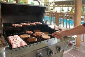 Ein Mann kocht Hamburger und Donuts auf einem Grill. in der Unterkunft Staybridge Suites Queretaro, an IHG Hotel in Querétaro